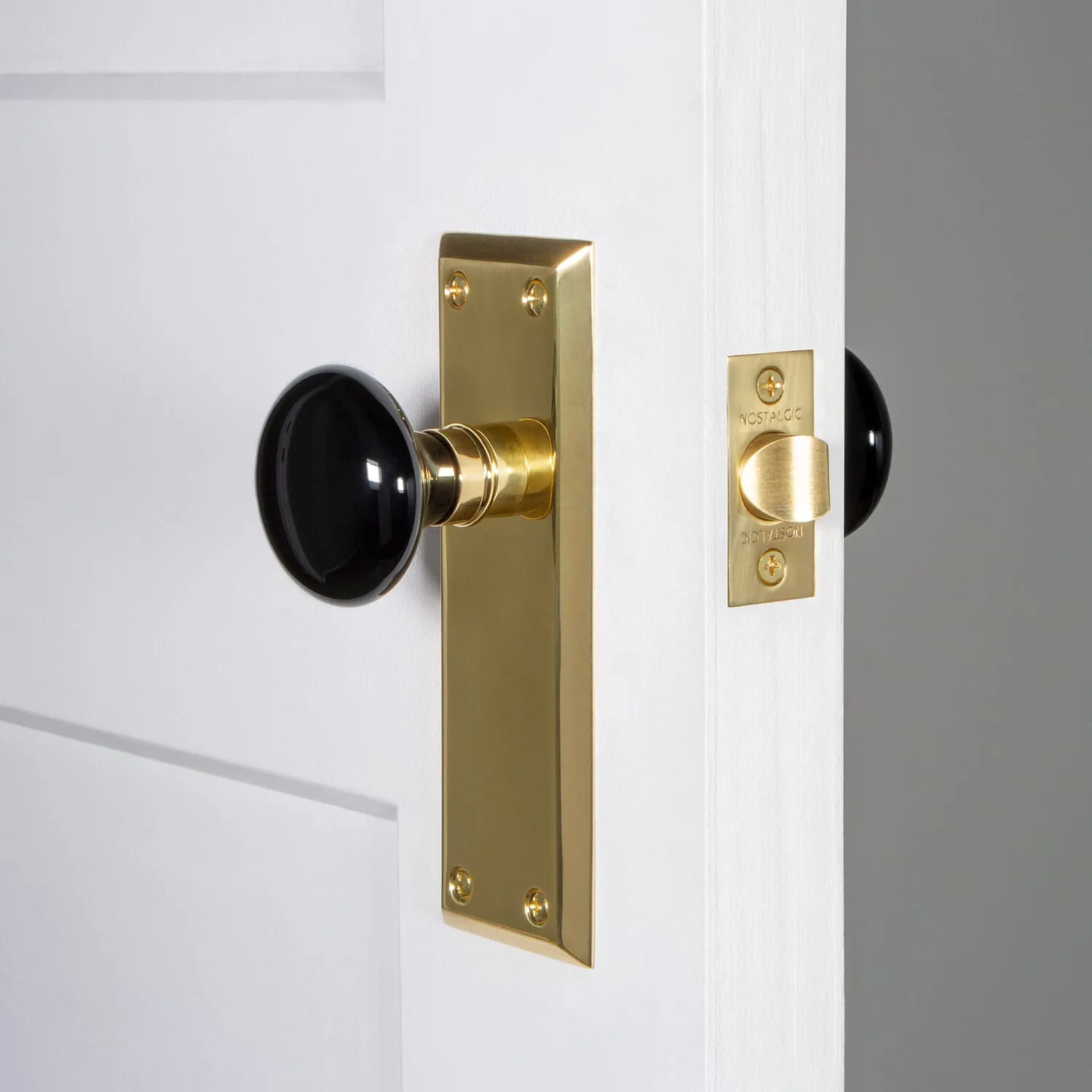 New York Long Plate with Black Porcelain Knob in Polished Brass